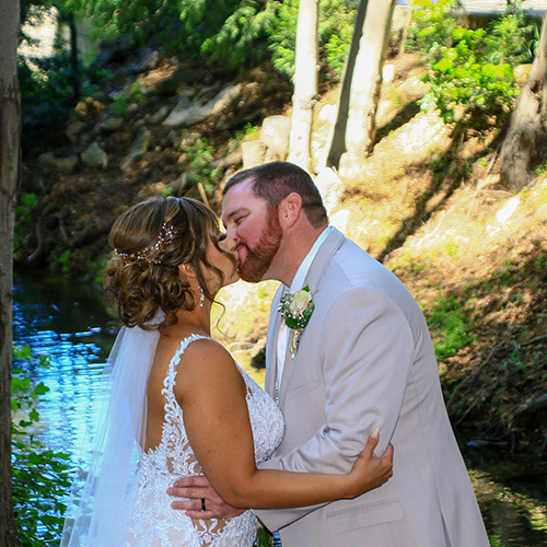 A bride and groom kissing in front of the water.