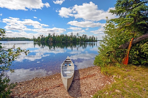 A canoe is parked on the shore of a lake.